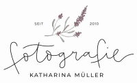 Delicate pink flowering branch arching over a faint cursive logo on a dark background, decorative emblem.